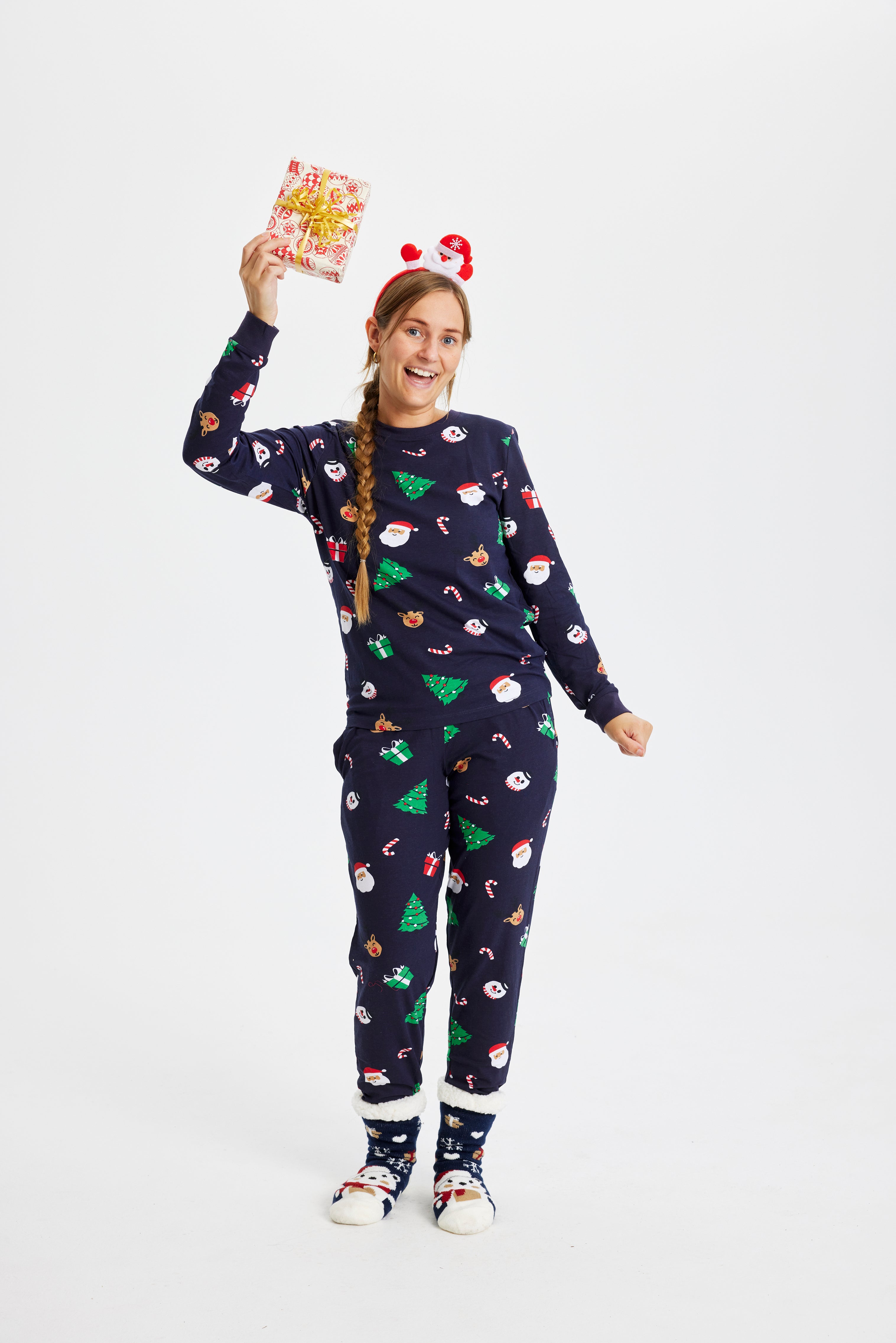 En kvinne i julepyjamas med en gave i hånden.